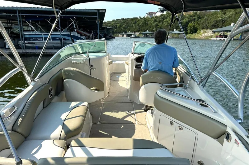 Slide: The Image of 2006 Sea Ray 240 Sundeck boat interior with driver, docked on a scenic lake. - 3