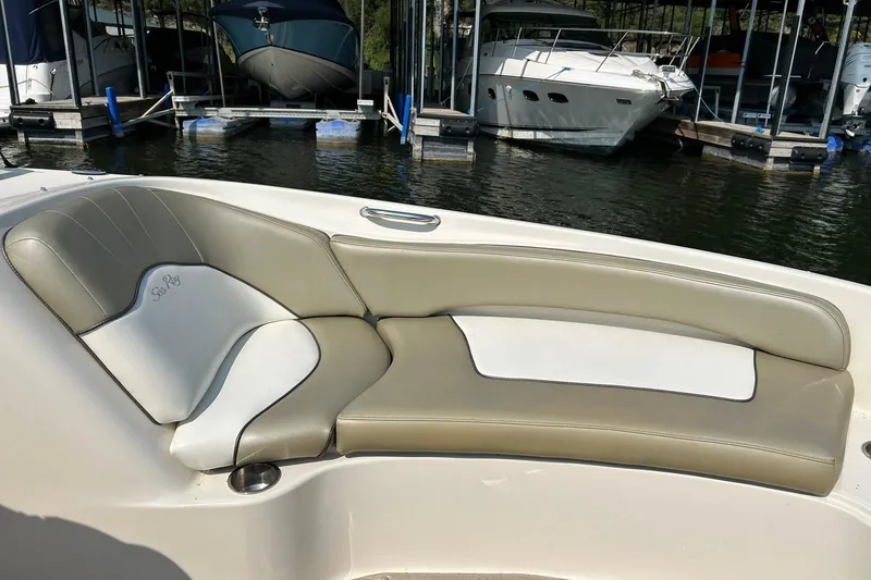 Slide: The Image of 2006 Sea Ray 240 Sundeck boat interior with beige and white seating at a marina. - 33