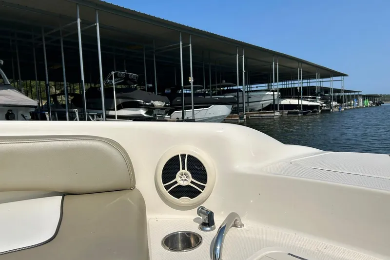 Slide: The Image of 2006 Sea Ray 240 Sundeck interior with marina view, featuring speaker and cup holder. - 34