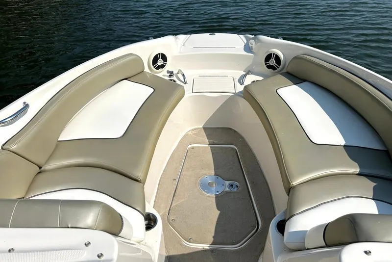 Slide: The Image of 2006 Sea Ray 240 Sundeck interior with beige seating, on calm water. - 5