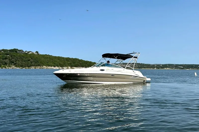 Slide: The Image of 2006 Sea Ray 240 Sundeck boat on calm water with scenic shoreline background. - 7