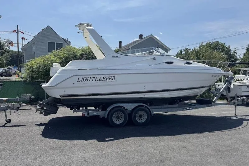 Slide: The Image of 2000 Weldcraft 26 Martinque boat named "Lightkeeper" on a trailer in a residential area. - 3