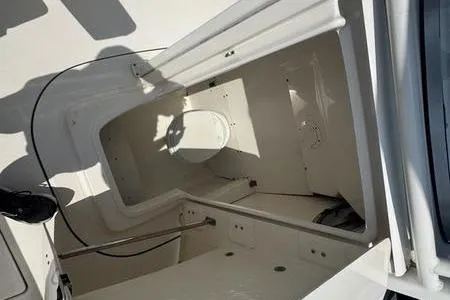 Slide: The Image of 2021 Robalo R242 boat storage compartment, open hatch, white interior, shadowed view. - 6