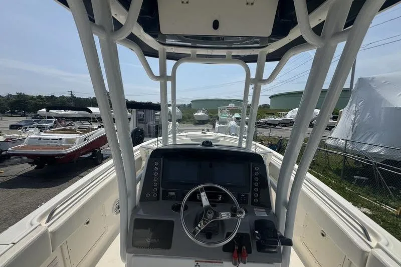 Slide: The Image of 2021 Robalo R242 boat dashboard with steering wheel and controls, docked in a marina. - 8