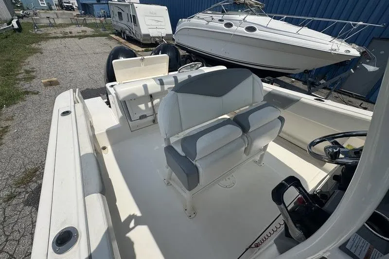Slide: The Image of 2021 Robalo R242 boat interior with dual seating and steering wheel, parked near other boats. - 9