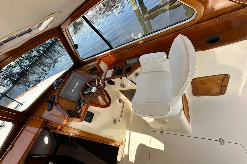 Slide: The Image of Interior of 2000 Hinckley Picnic Boat 36 with helm, steering wheel, and white captain's chair. - 14