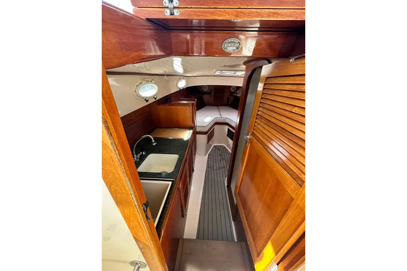 Slide: The Image of Interior of 2000 Hinckley Picnic Boat 36 with wood finish and compact kitchen. - 16