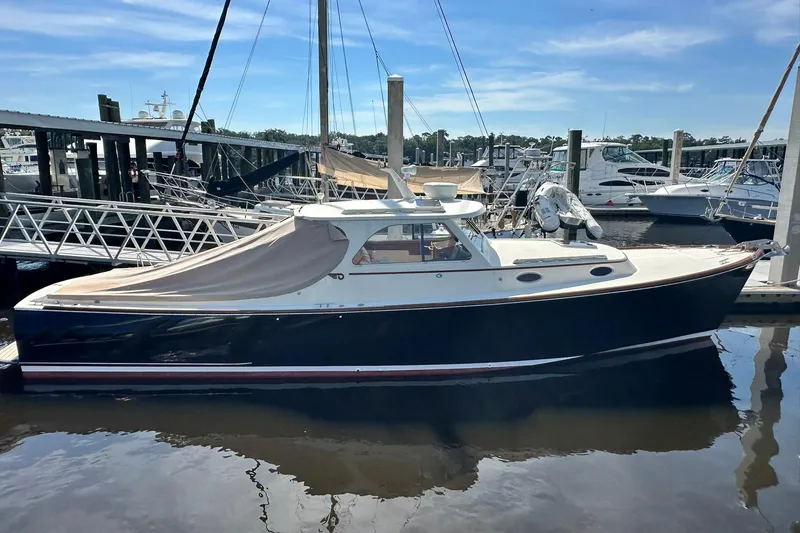 The Image of 2000 Hinckley Picnic Boat 36 docked at marina under clear blue sky. - 0