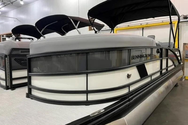 The Image of 2025 Bennington 24MSB pontoon boat in showroom with black canopy and sleek design. - 0