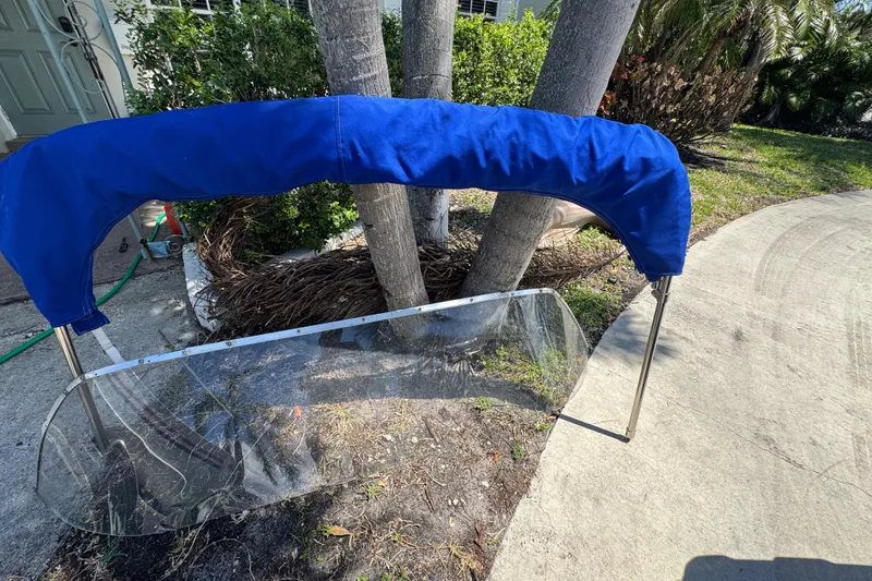 Slide: The Image of 1960 Crestliner Wildwood 19 windshield with blue cover, outdoors near palm trees. - 11