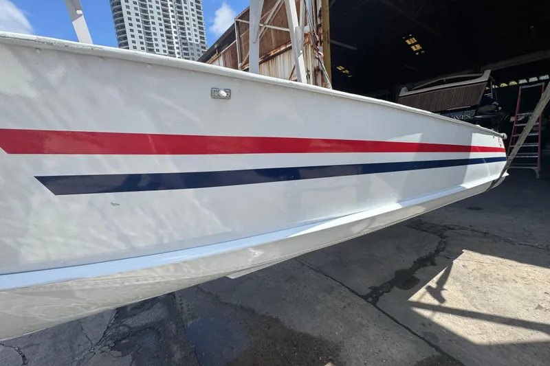 Slide: The Image of 1960 Crestliner Wildwood 19 boat with red and blue stripes, docked near a building. - 16