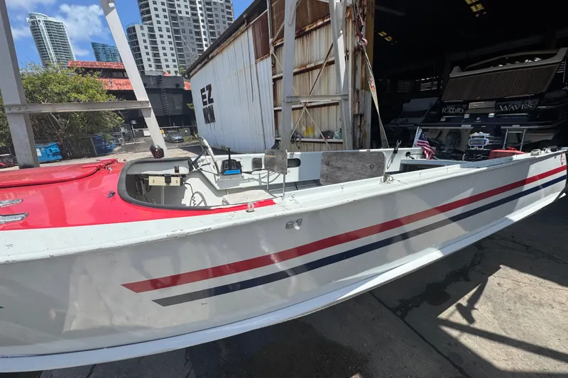 Slide: The Image of 1960 Crestliner Wildwood 19 boat with red and white design, docked near urban buildings. - 17