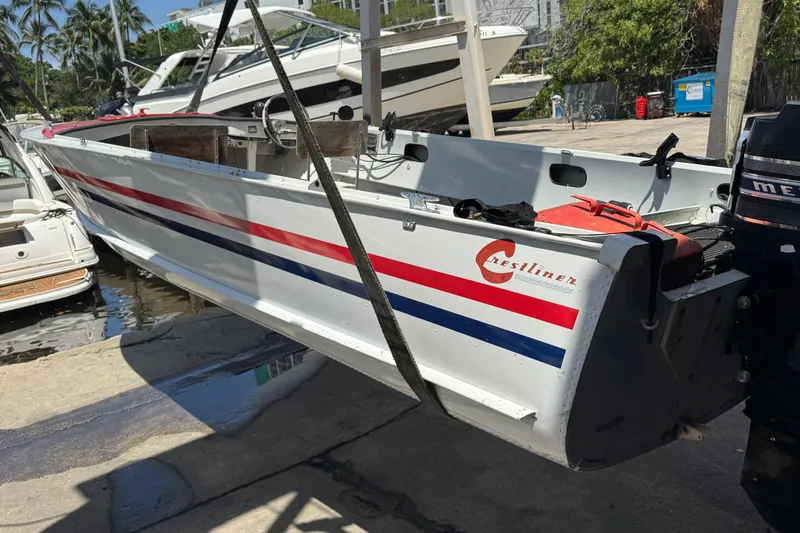 Slide: The Image of 1960 Crestliner Wildwood 19 boat with red and blue stripes, docked near other boats. - 20