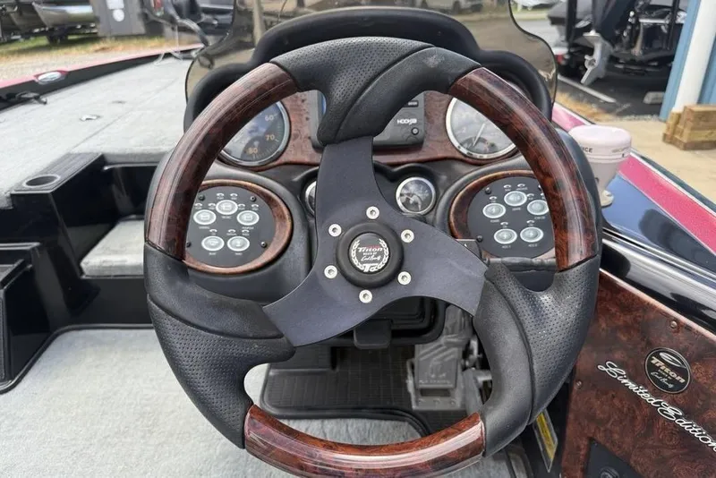 Slide: The Image of Steering wheel of a 2005 Triton TR 19 X boat, featuring wood and leather accents. - 12