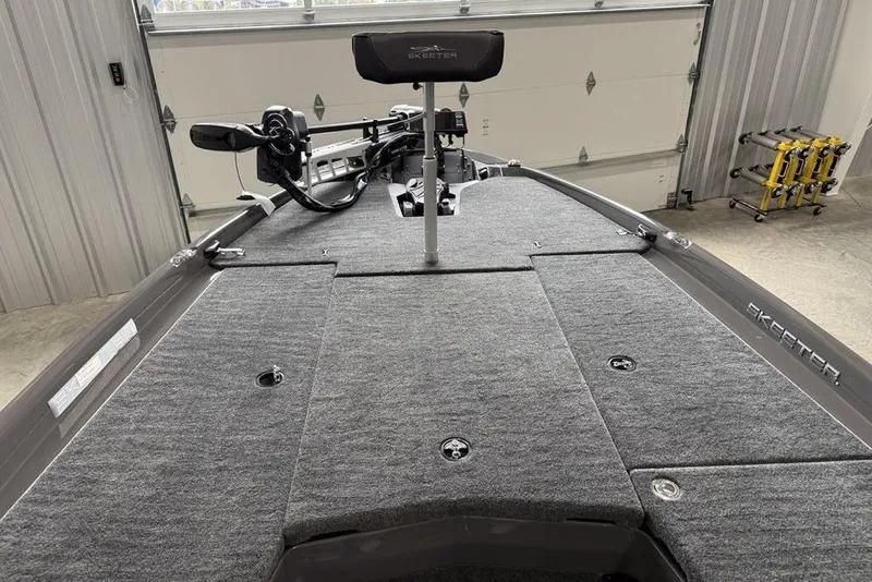 Slide: The Image of 2025 Skeeter ZXR20 boat interior with gray carpeted deck in a garage setting. - 8
