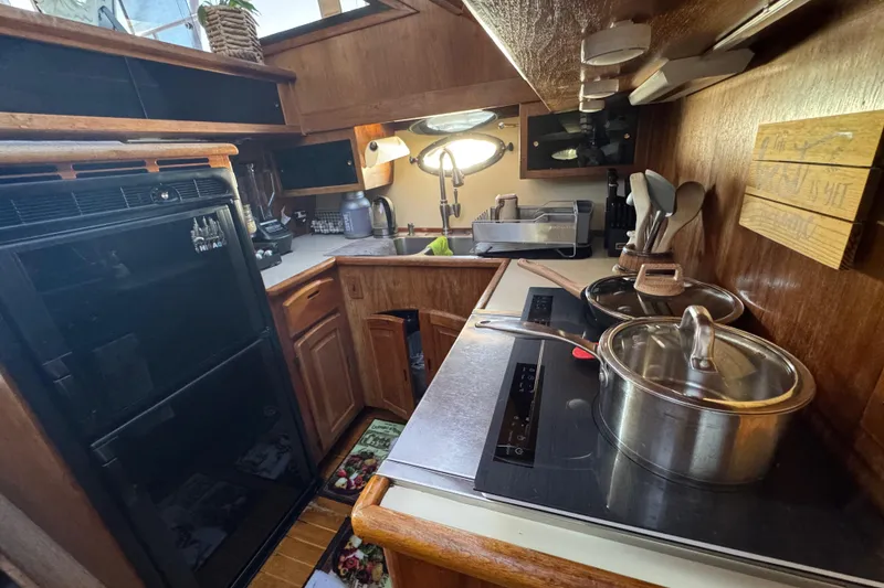 Slide: The Image of Compact kitchen in a 1986 Californian 42 yacht, featuring modern appliances and wooden cabinetry. - 12