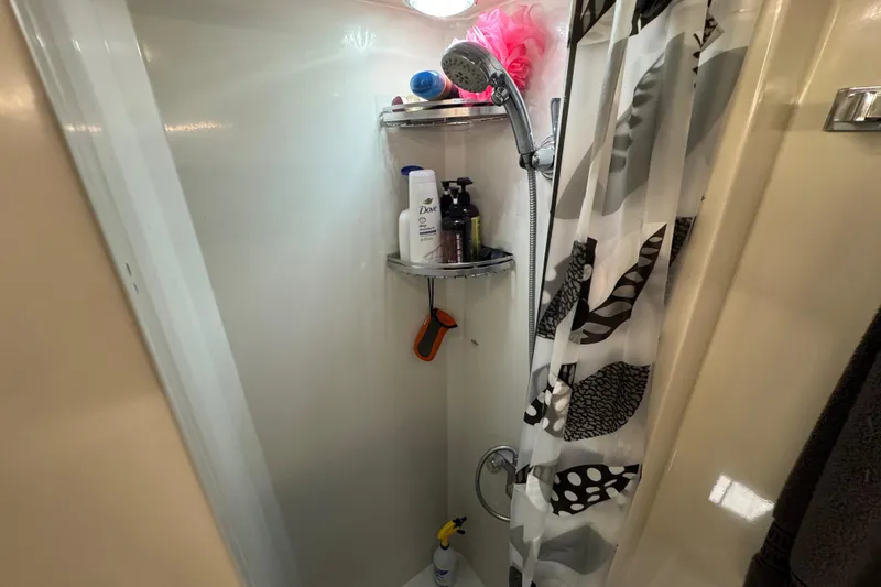 Slide: The Image of Compact shower in a 1986 Californian 42 boat, featuring toiletries and a patterned curtain. - 23