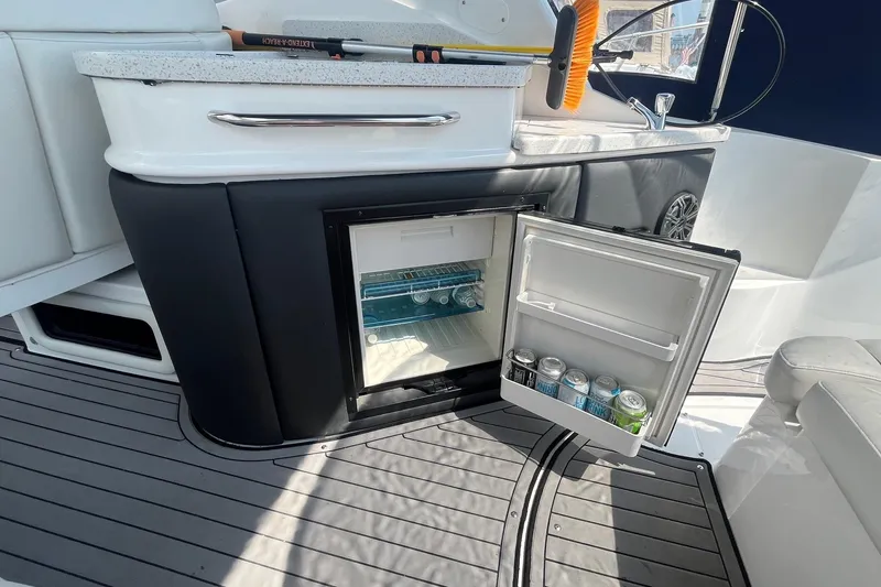 Slide: The Image of 2020 Rinker 290 EX boat interior with open mini fridge stocked with drinks. - 11