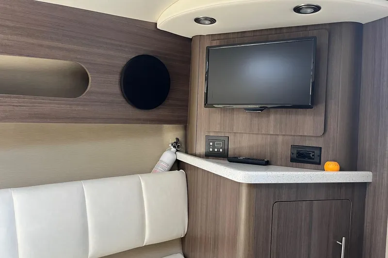 Slide: The Image of 2020 Rinker 290 EX interior with TV, modern cabinetry, and seating area. - 19
