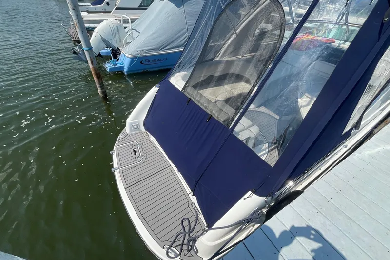 Slide: The Image of 2020 Rinker 290 EX boat docked with blue canopy and swim platform. - 2