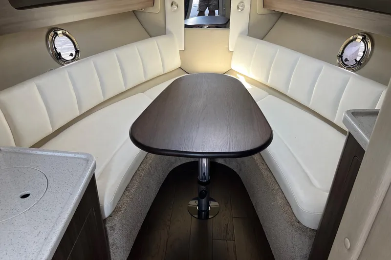Slide: The Image of 2020 Rinker 290 EX cabin interior with white seating and wooden table. - 20