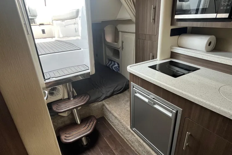 Slide: The Image of Interior of 2020 Rinker 290 EX boat with kitchenette and cabin area. - 22
