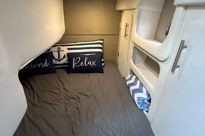 Slide: The Image of 2020 Rinker 290 EX cabin interior with cozy bedding and nautical-themed pillows. - 24