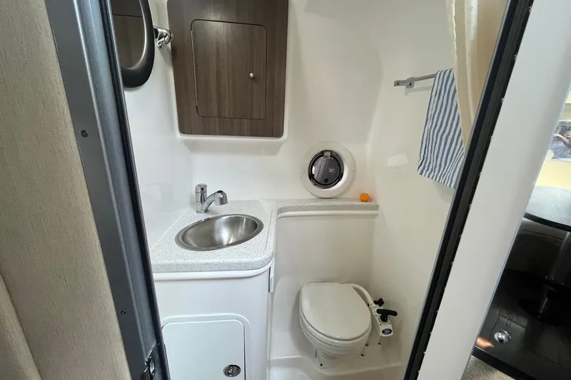 Slide: The Image of 2020 Rinker 290 EX boat bathroom with sink, toilet, and storage cabinet. - 27