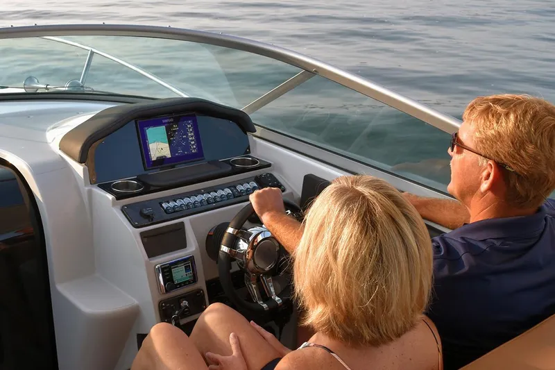Slide: The Image of Manufacturer Provided Image: Couple navigating a 2020 Rinker 290 EX boat on calm waters. - 32