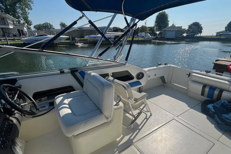 Slide: The Image of 1991 Sea Ray 300 Weekender boat interior with seating and steering, docked by a serene waterfront. - 10