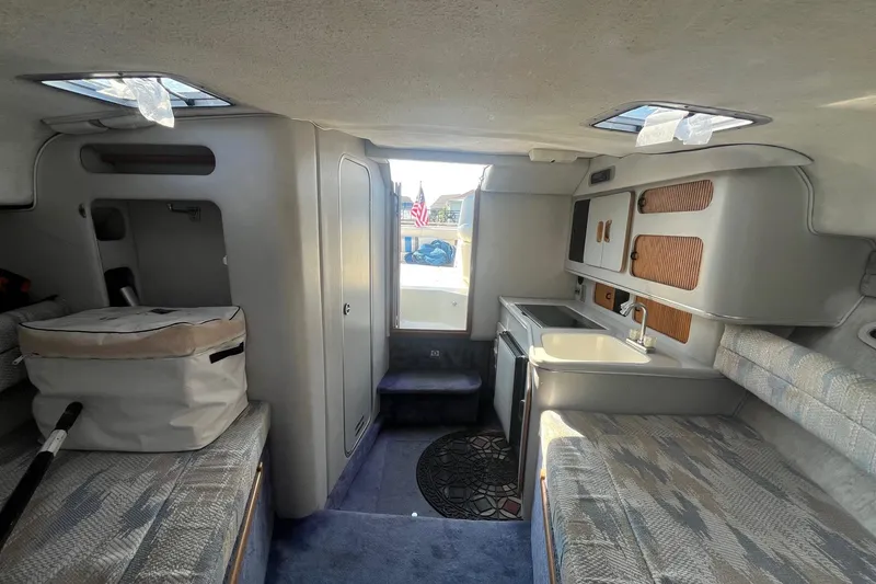 Slide: The Image of Interior of a 1991 Sea Ray 300 Weekender boat, featuring a compact kitchen and seating area. - 14