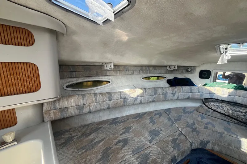 Slide: The Image of Interior of a 1991 Sea Ray 300 Weekender boat with cushioned seating and windows. - 15