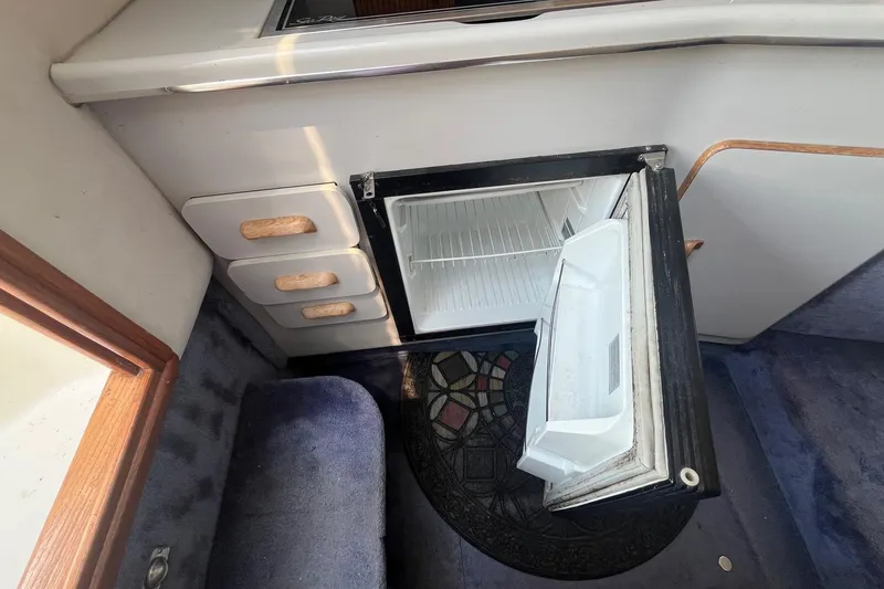 Slide: The Image of 1991 Sea Ray 300 Weekender interior with open mini fridge and carpeted flooring. - 19
