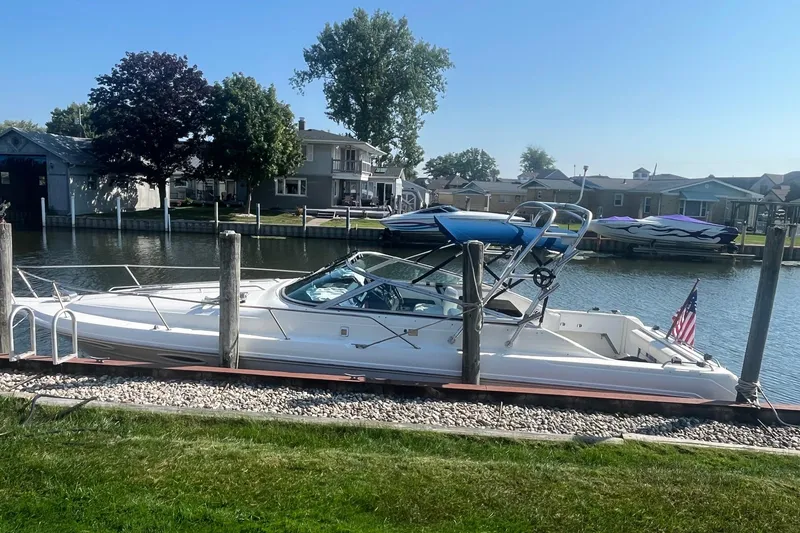Slide: The Image of 1991 Sea Ray 300 Weekender docked by a serene waterfront with houses in the background. - 2