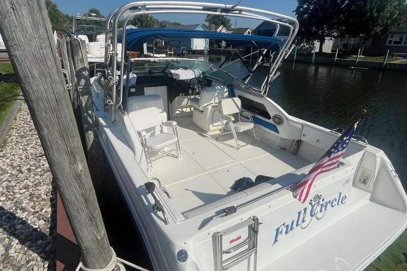 Slide: The Image of 1991 Sea Ray 300 Weekender boat docked, featuring spacious deck and American flag. - 3