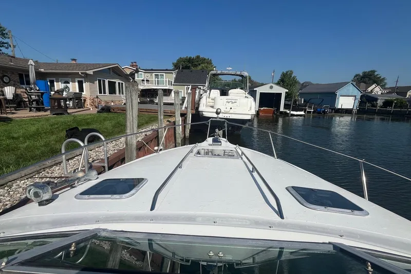 Slide: The Image of 1991 Sea Ray 300 Weekender docked near waterfront homes under clear blue sky. - 4