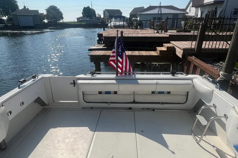 Slide: The Image of 1991 Sea Ray 300 Weekender boat docked, featuring spacious deck and American flag. - 6