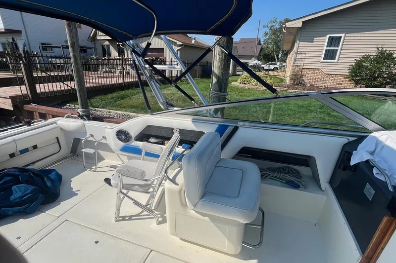Slide: The Image of 1991 Sea Ray 300 Weekender boat interior with seating and canopy, docked near a house. - 9