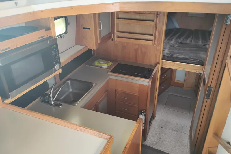 Slide: The Image of 1985 Mainship 34 Mk III interior with kitchen, microwave, sink, stove, and cozy sleeping area. - 18