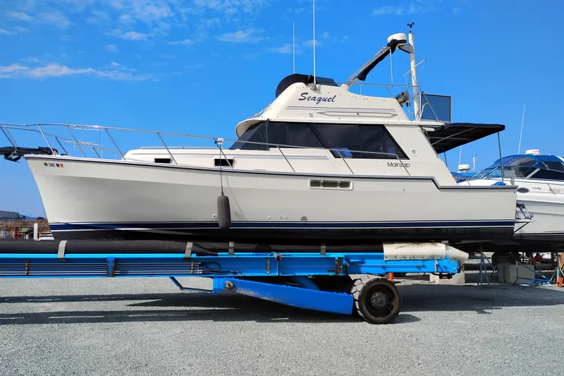 Slide: The Image of 1985 Mainship 34 Mk III boat on trailer under clear blue sky. - 2