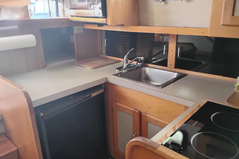 Slide: The Image of 1985 Mainship 34 Mk III boat kitchen with sink, stove, and wooden cabinetry. - 21