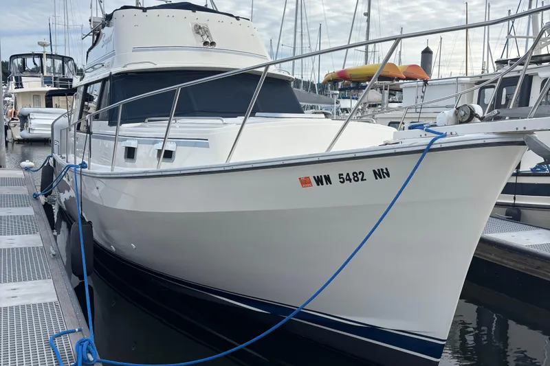 Slide: The Image of 1985 Mainship 34 III docked at marina, white hull, blue trim, registration visible. - 3