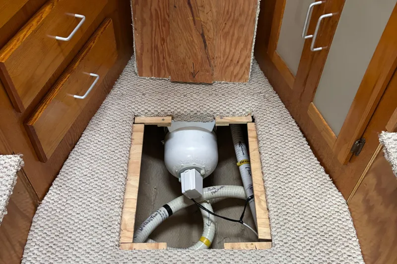 Slide: The Image of 1985 Mainship 34 III interior showing plumbing access under carpeted floor. - 30