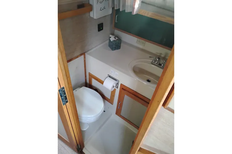 Slide: The Image of 1985 Mainship 34 Mk III bathroom with toilet, sink, and wooden cabinetry. - 31