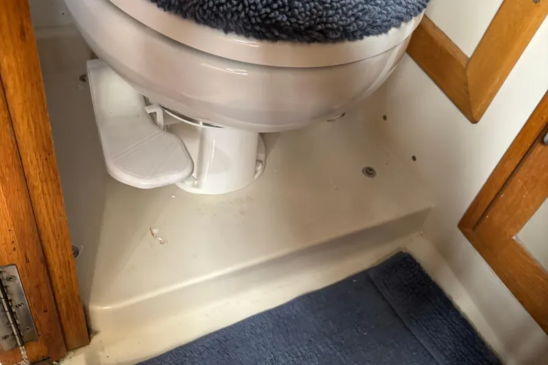 Slide: The Image of 1985 Mainship 34 III boat bathroom with toilet and blue rug. - 33