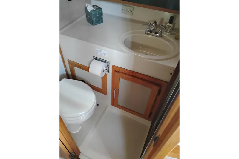 Slide: The Image of 1985 Mainship 34 Mk III bathroom with sink, toilet, and wooden cabinetry. - 34