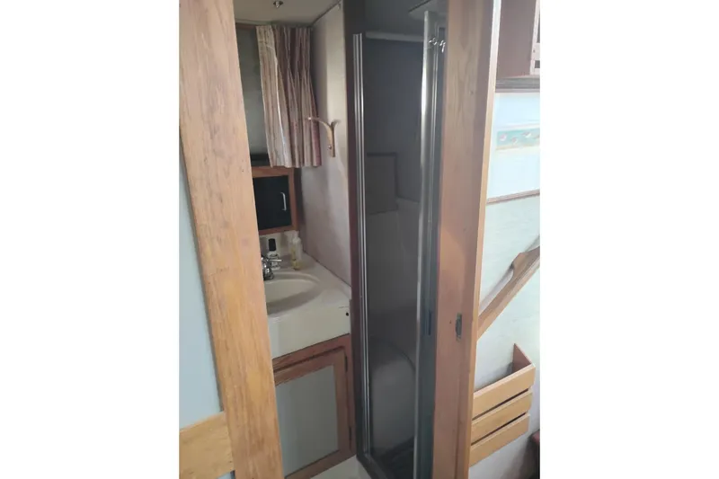 Slide: The Image of 1985 Mainship 34 Mk III bathroom with sink, shower, and wooden cabinetry. - 36