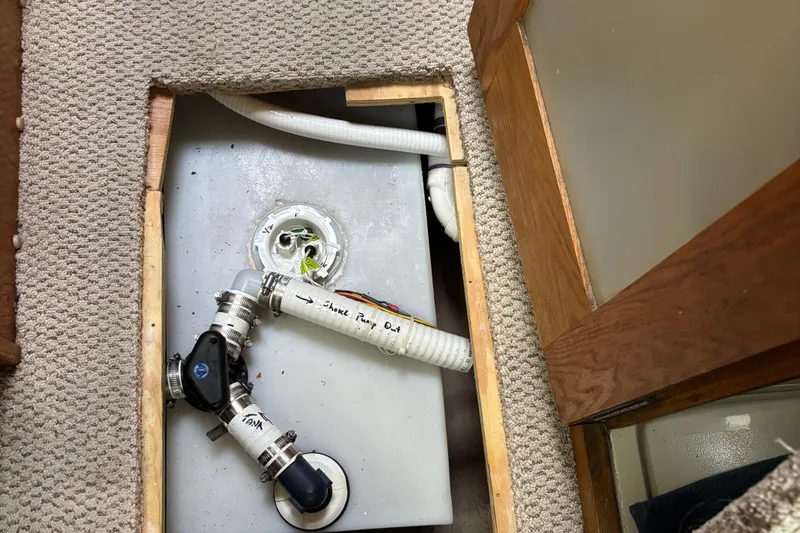 Slide: The Image of 1985 Mainship 34 III plumbing system with exposed pipes and fittings under carpeted floor. - 37