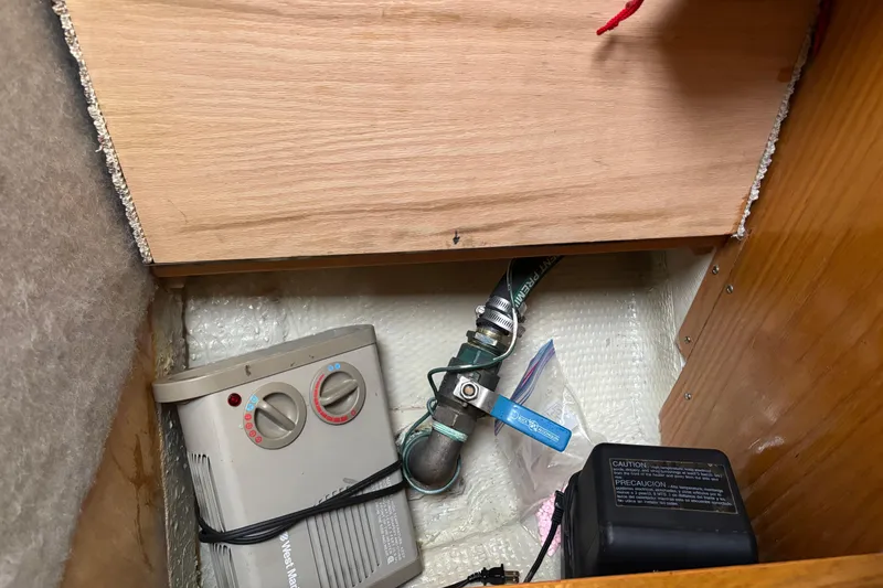 Slide: The Image of 1985 Mainship 34 III interior compartment with heater and plumbing components. - 38