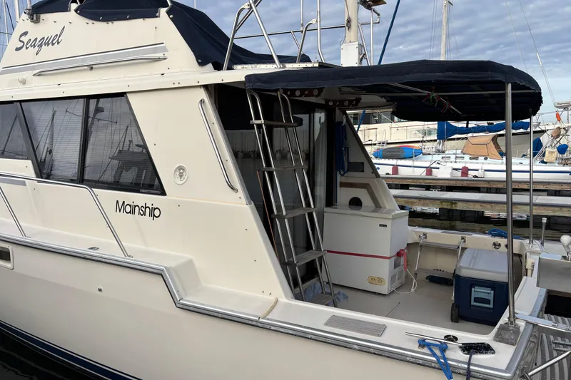 Slide: The Image of 1985 Mainship 34 III docked, featuring a ladder and covered deck area. - 5